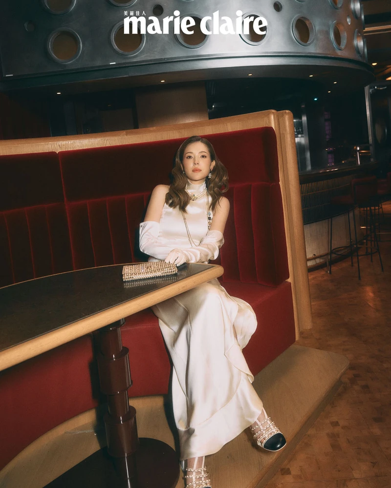 白色緞面削肩長洋裝與手套、多彩寶石長鍊、水鑽珍珠手拿宴會包、黑白雙色皮穿鍊粗跟涼鞋，all by Chanel。