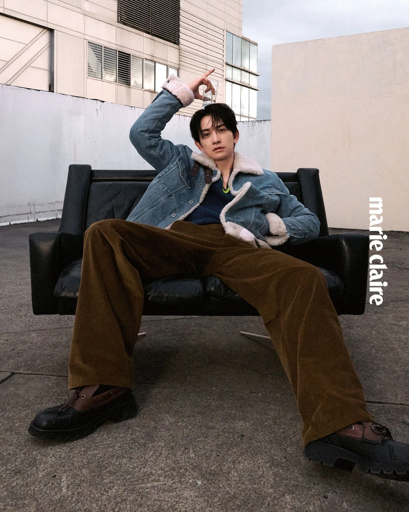 丹寧卡車司機外套、黃藍色V領針織衫、棕色長褲、小牛皮撞色德比鞋，All by Loewe。