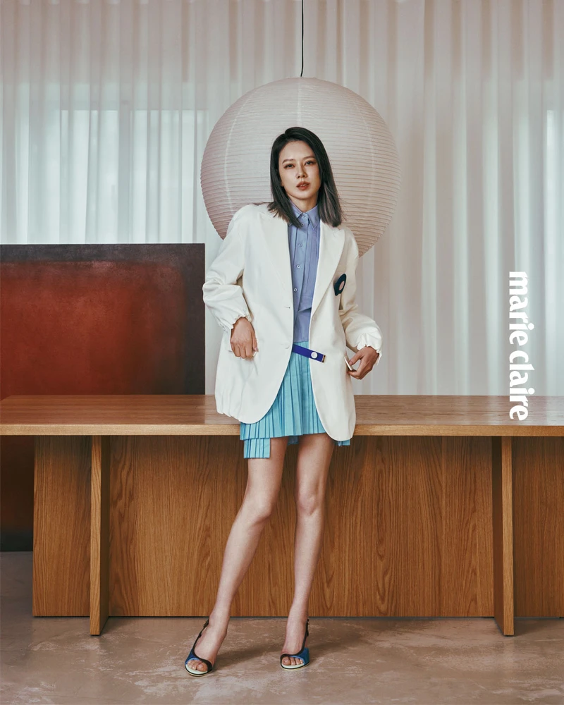 白色西裝外套、灰藍色無袖短板襯衫、水藍色不對稱百褶短裙、藍色露跟鏤空高跟涼鞋，all by Fendi。