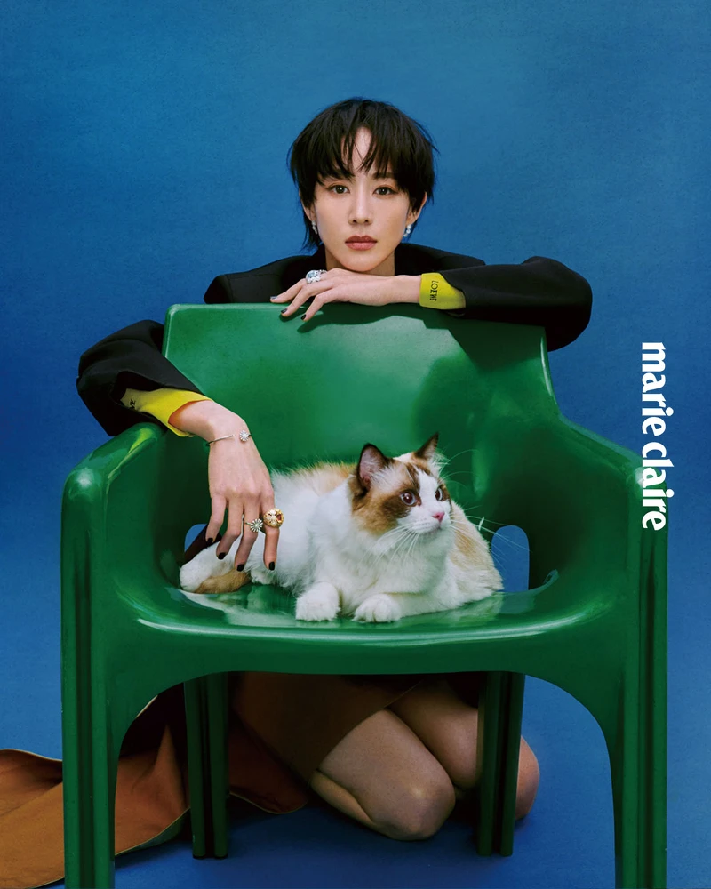 黑色西裝外套、半高領黃色上衣、駝色不對稱裙，all by Loewe； Margherita 瑪格麗特系列18K 黃金黃水晶與鑽石項鍊、Margherita 瑪格麗特系列18K 白金鑽石九朵花卉項鍊、Margherita 瑪格麗特系列18K白金鑽石花卉手環、Margherita 瑪格麗特系列18K 白金鑽石花卉耳環、兩只 Margherita 瑪格麗特系列18K 白金鑽石花卉戒指，Margherita 瑪格麗特系列18K 白金海水藍寶石與鑽石戒指，all by DAMIANI。